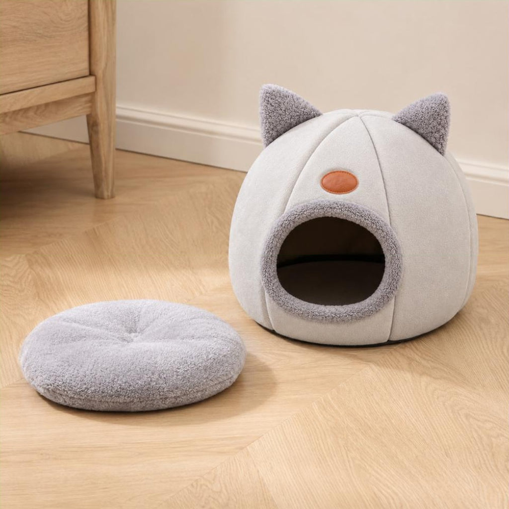 Nid pour chat gris clair posé au sol avec son coussin intérieur sorti à côté