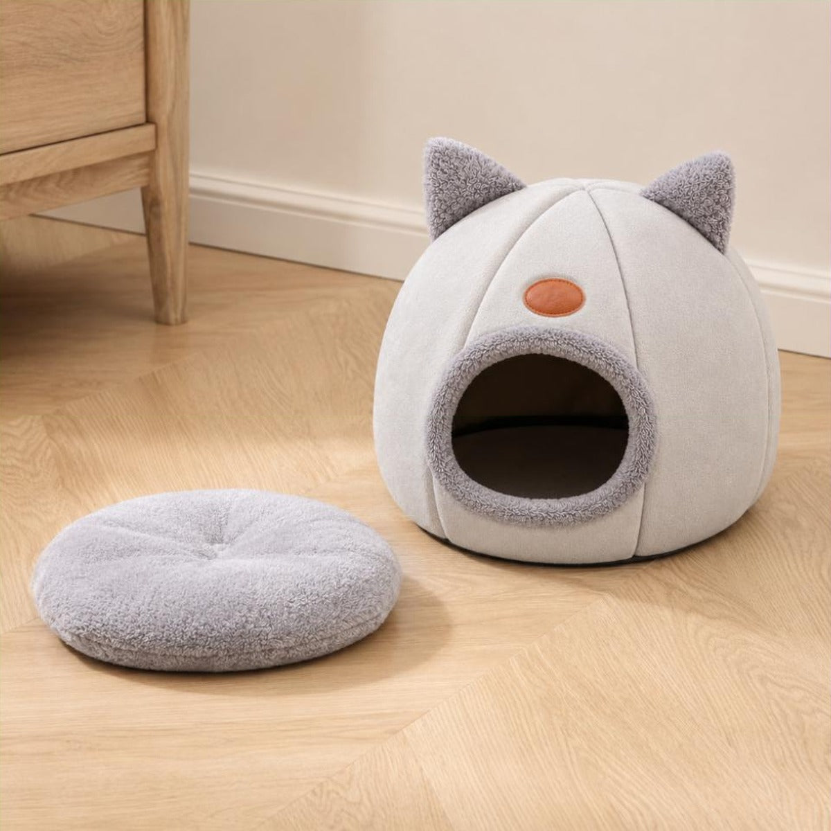 Nid pour chat gris clair posé au sol avec son coussin intérieur sorti à côté